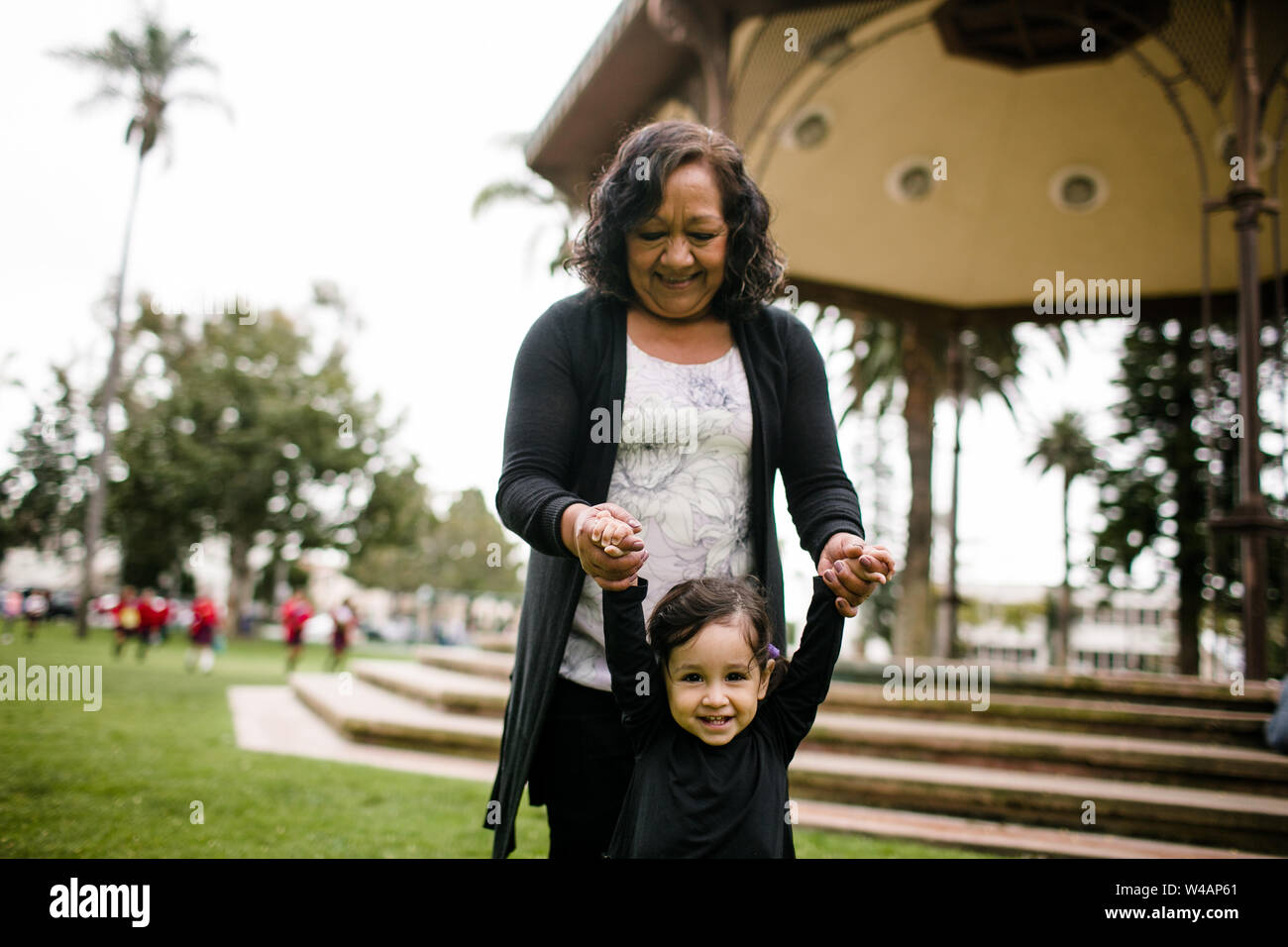 Grandmother holding granddaughter's hands while standing in park Stock Photo