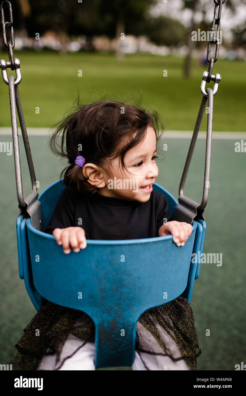 Little girl sitting in swing smiling Stock Photo