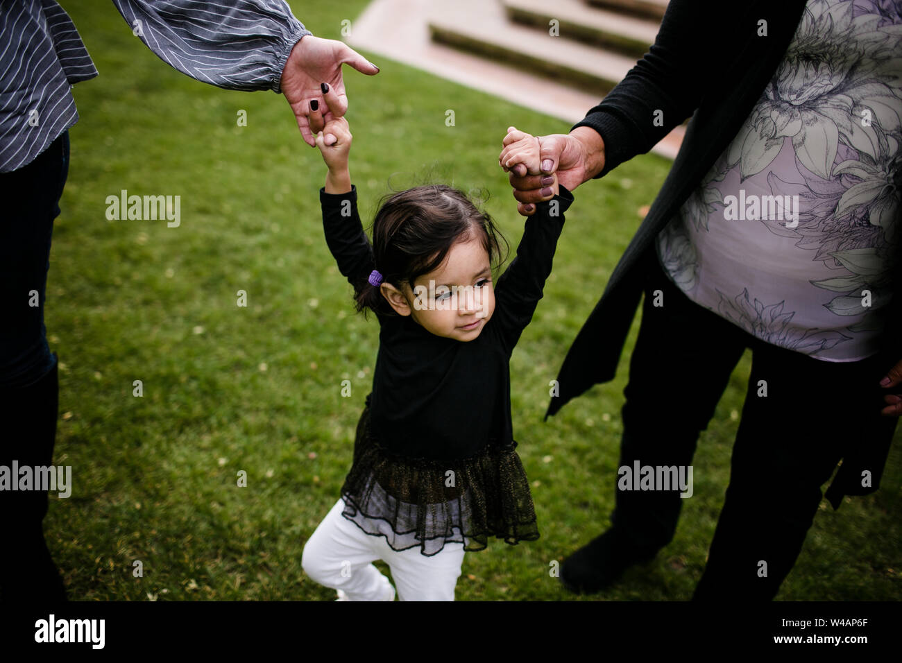 Little girl standing while holding hands with mother and grandmother Stock Photo