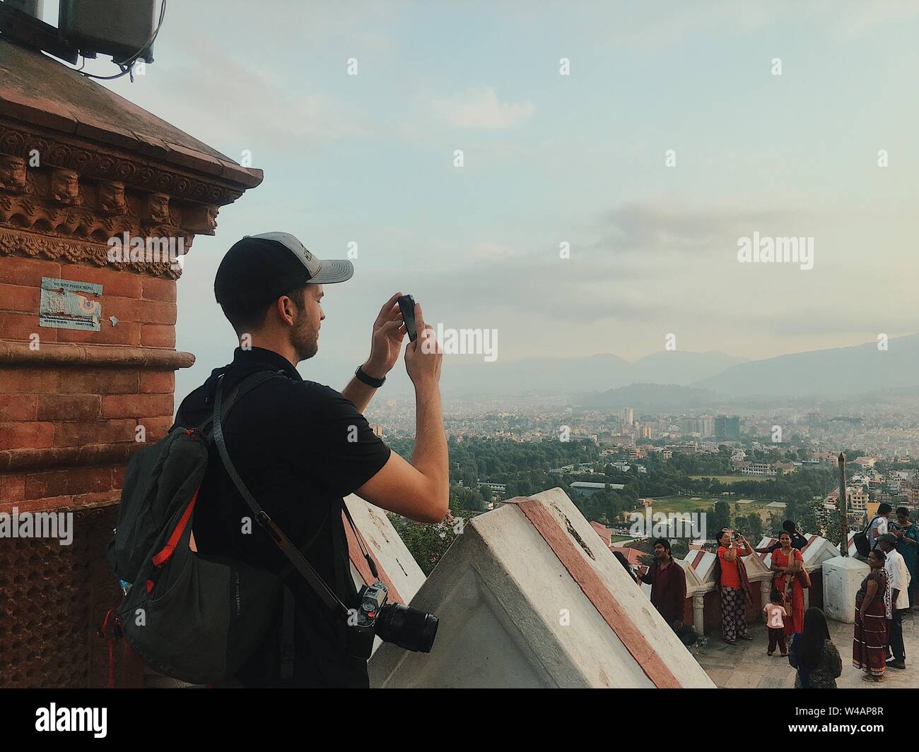 Man taking picture on phone overlooking city in Nepal Stock Photo