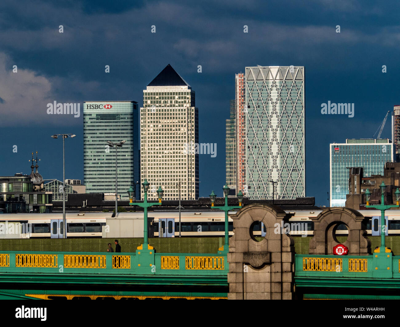 Canary Wharf London against dark skies. Canary Wharf view from Central London with Southwark Bridge and Cannon Street Rail bridge in the foreground Stock Photo