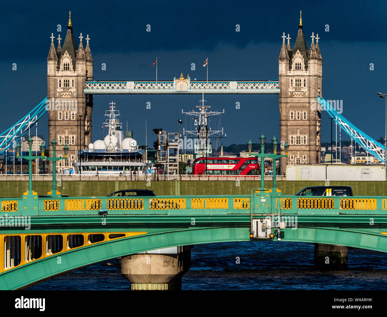 Tower Bridge London under stormy sky. Iconic Tower Bridge against a dark sky with Southwark Bridge and London Bridge traffic visible in the foreground Stock Photo