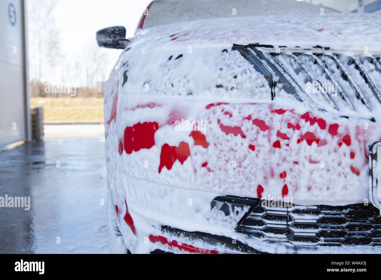 Car cleaning. Wash red car with soap. High pressure water washing close
