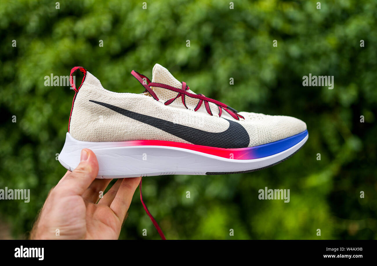 Paris, France - Jul 8, 2019: Athlete man hand holding presenting new  running shoes Nike Zoom Fly Flyknit against green background - side view  with logotype insignia Stock Photo - Alamy