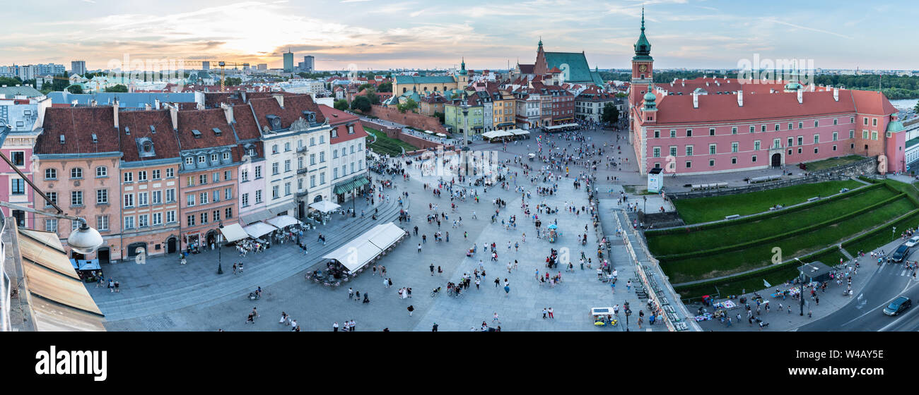 Panoramic view of Castle Square in Warsaw, Poland, as the sun begins to set over the Old Town with people outside Sigismund's Column and Royal Castle. Stock Photo