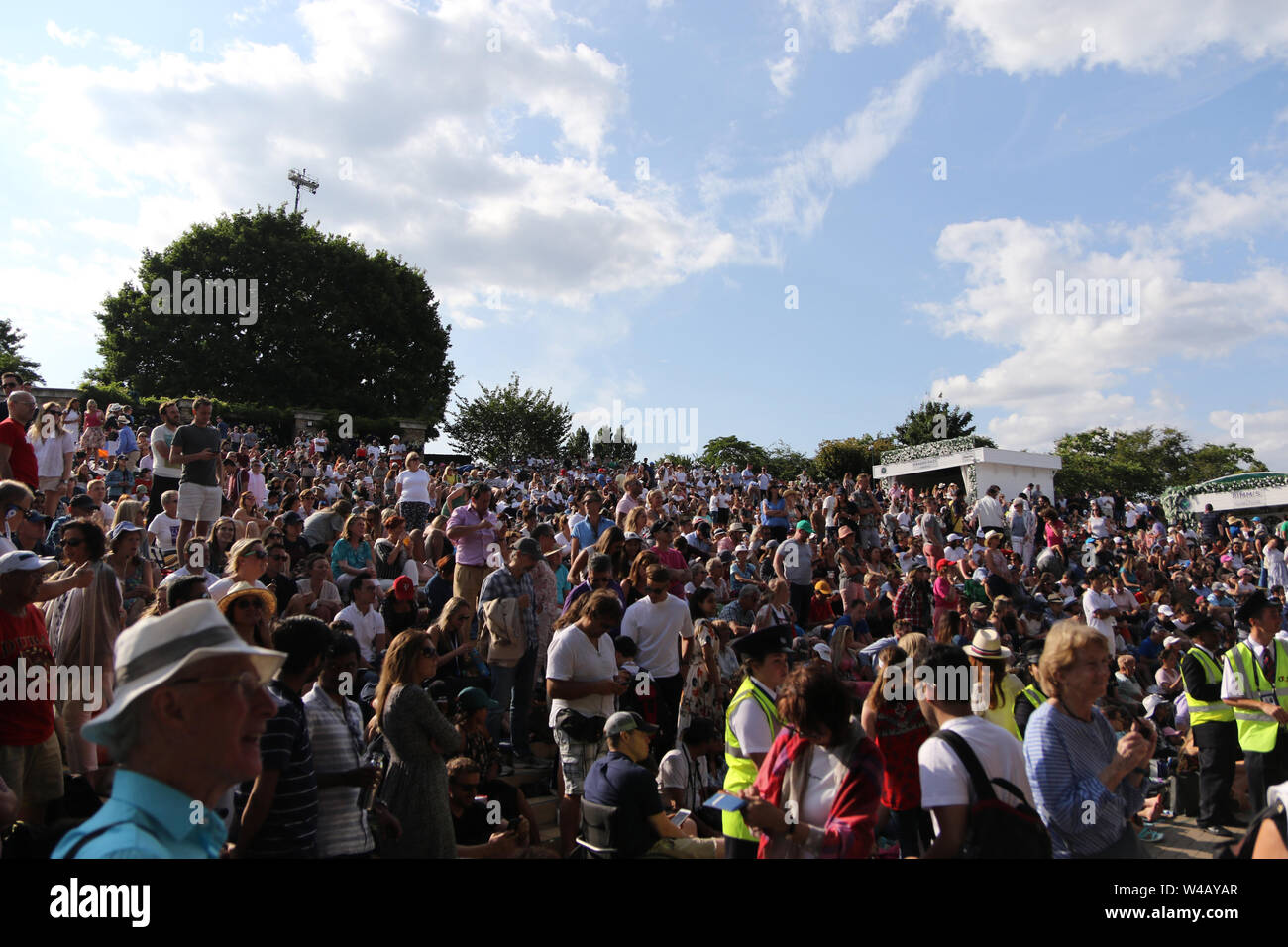 During the 2019 tennis championships crowds sat on 'Henman Hill' or 'Murray Mound'. Aorangi Terrace, commonly known as 'Henman Hill', alongside a series of other nicknames, is a mostly grassed banked area in the grounds of the All England Lawn Tennis and Croquet Club where, during the annual Wimbledon tennis championship, crowds of people without showcourt tickets can watch the tennis matches live on a giant television screen at the side of No. 1 Court. The terrace is also the main site for spectators to eat picnics.During television broadcasts of matches, cameras often sweep over the area. Stock Photo