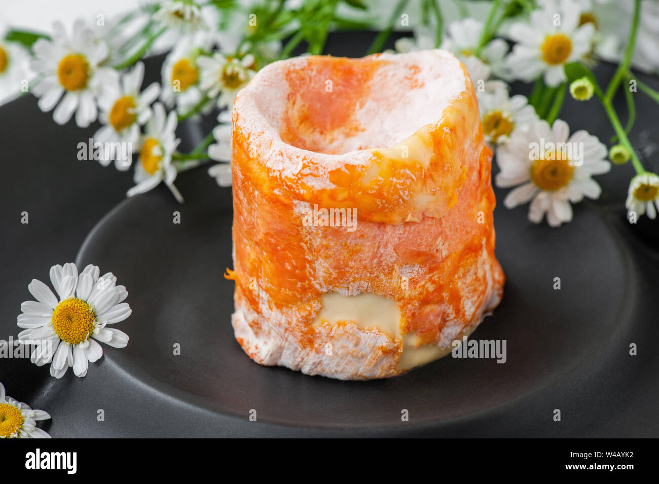 French soft cheese with white mold orange rind epoisses on a black