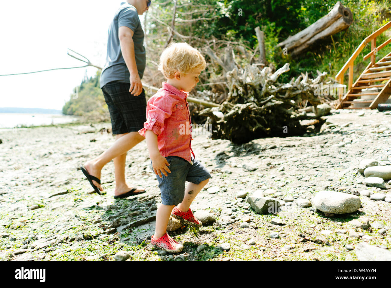 Side view of a father and son walking on a rocky beach on a sunny day Stock Photo