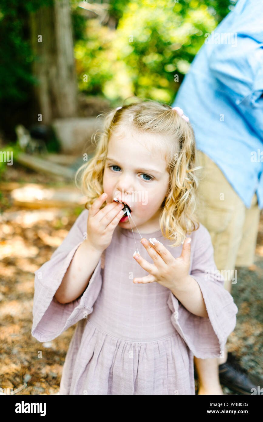 Straight on view of a young girl eating a messy marshmallow s'more Stock Photo