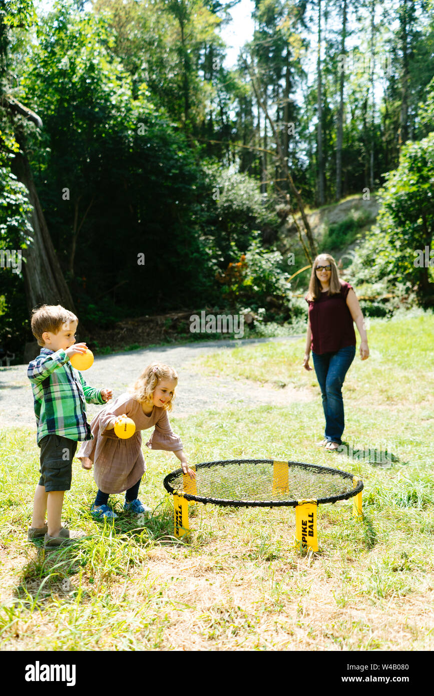 Children playing games together at a campsite while their mom watches Stock Photo