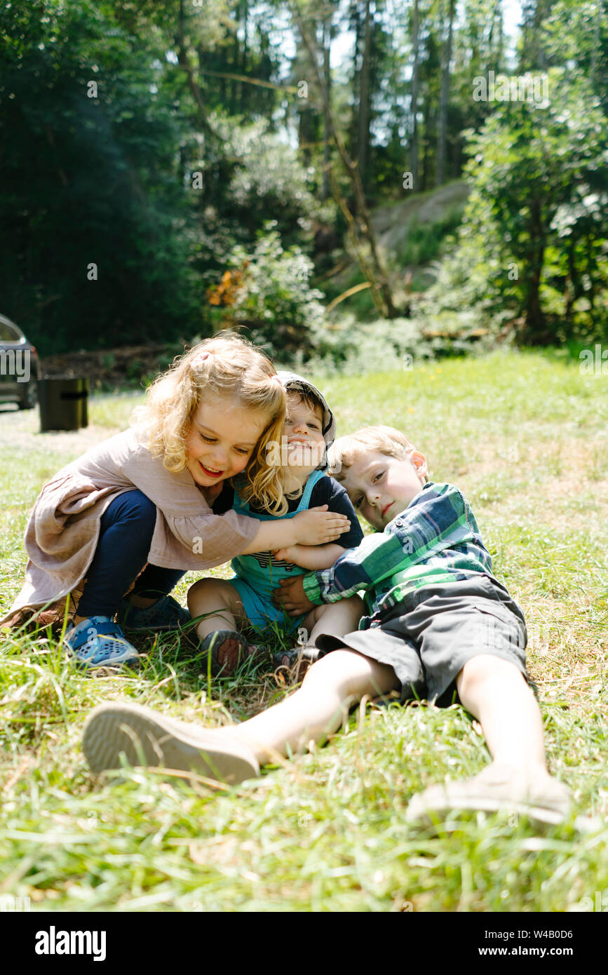 Closeup view of three young children hugging on a summer day Stock Photo