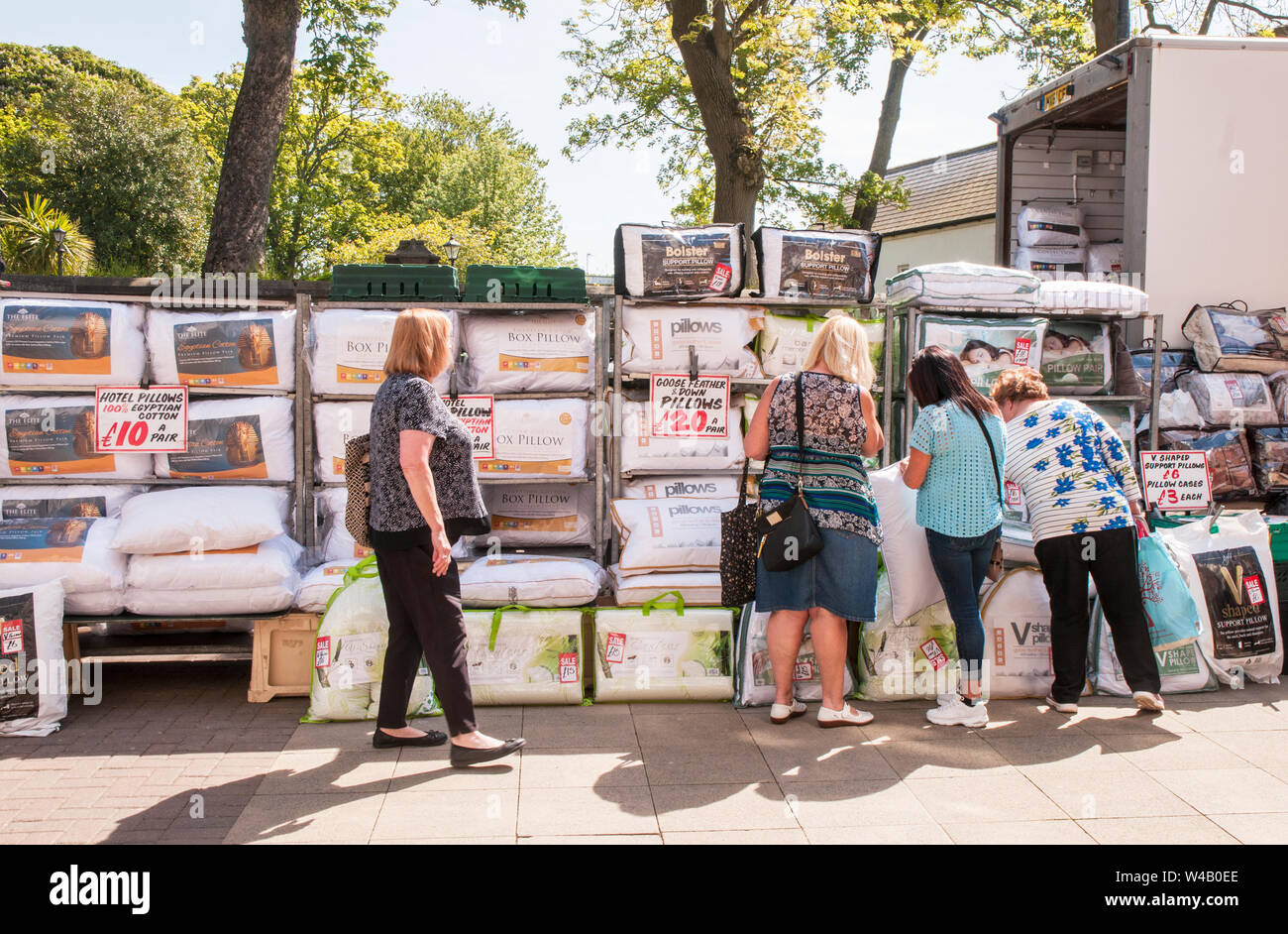 Ladies looking at items from mobile shop selling bed linen etc on weekly market at Poulton le Fylde Lancashire England UK Stock Photo