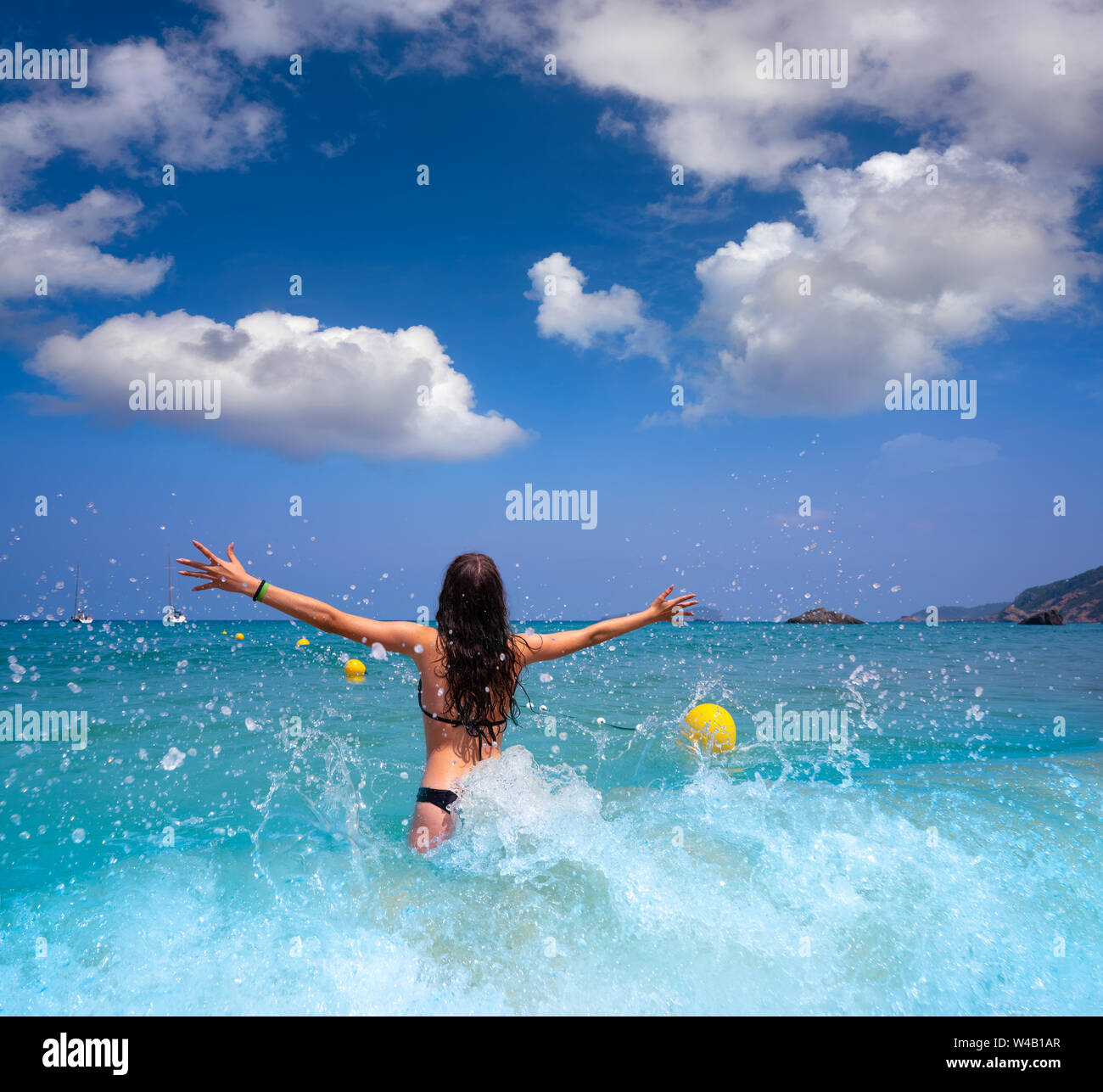 Ibiza beach girl splashing water open arms in Balearic islands Stock Photo