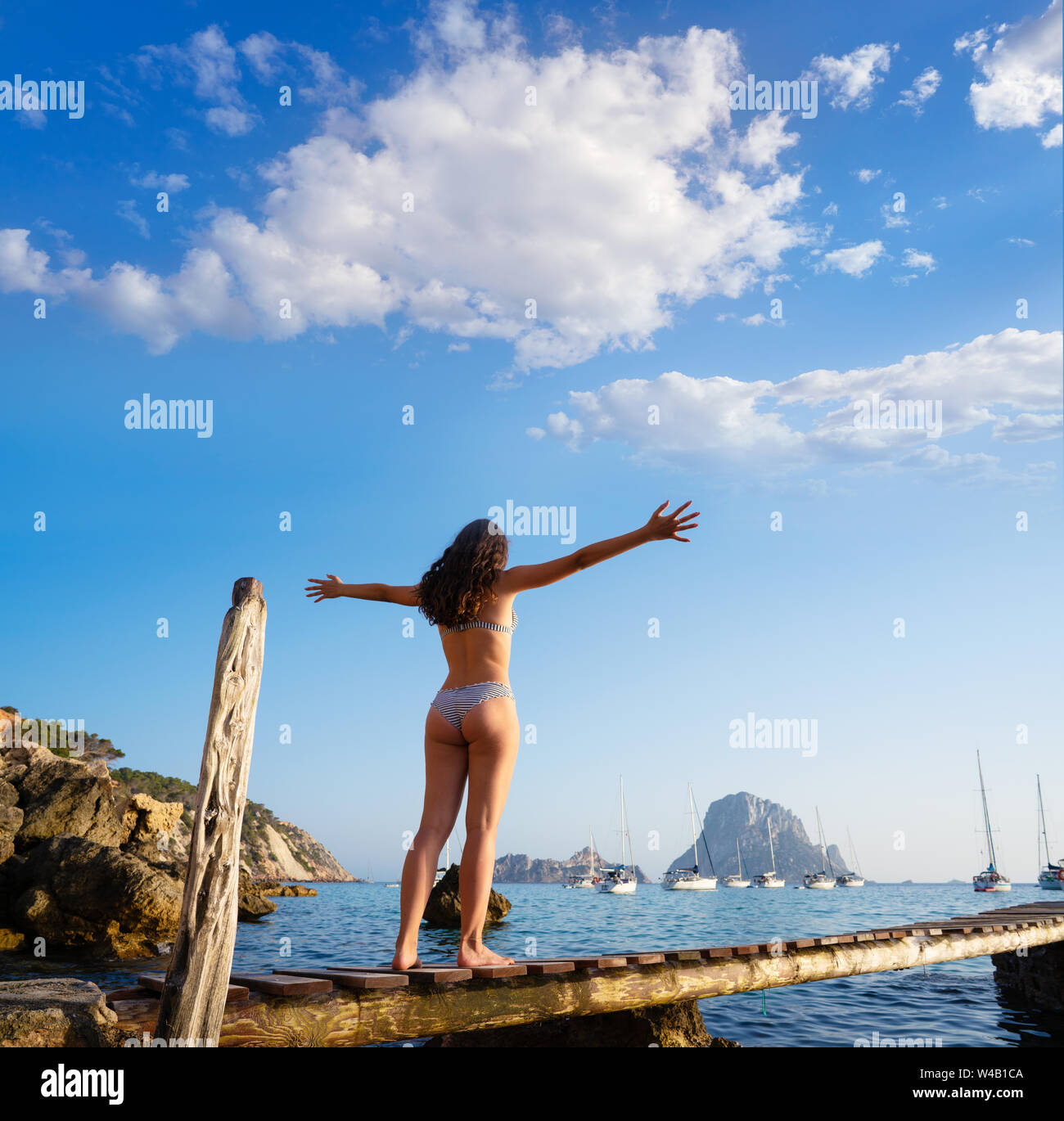 Ibiza cala d Hort girl open arms on pier sunset Es Vedra islet Balearic Islands Stock Photo