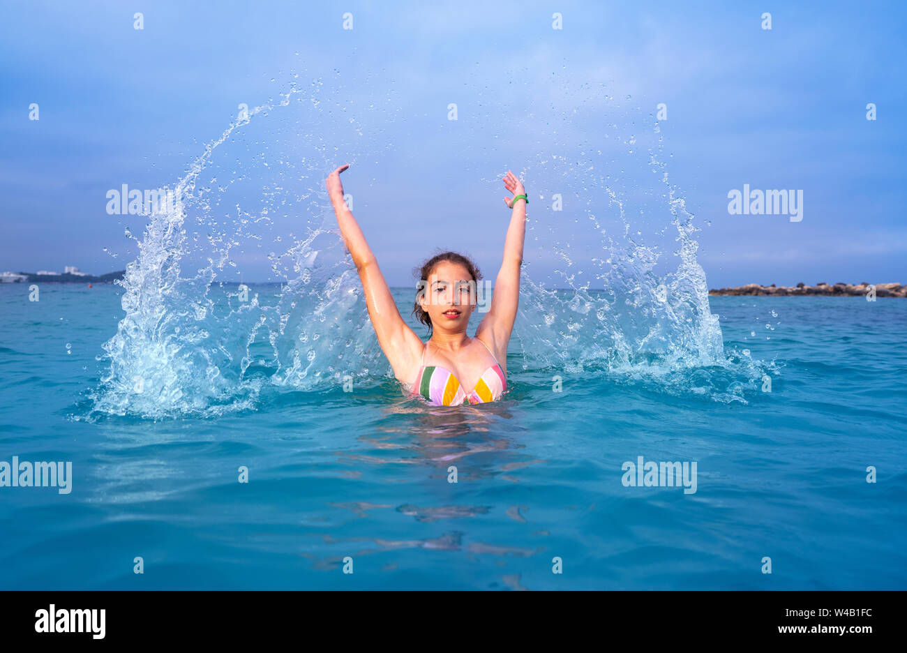 Young woman girl water splash in Ibiza beach of Santa Eulalia at Balearic Islands Stock Photo