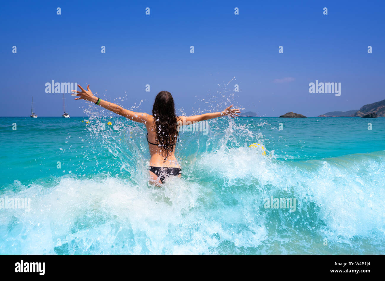 Ibiza beach girl splashing water open arms in Balearic islands Stock Photo