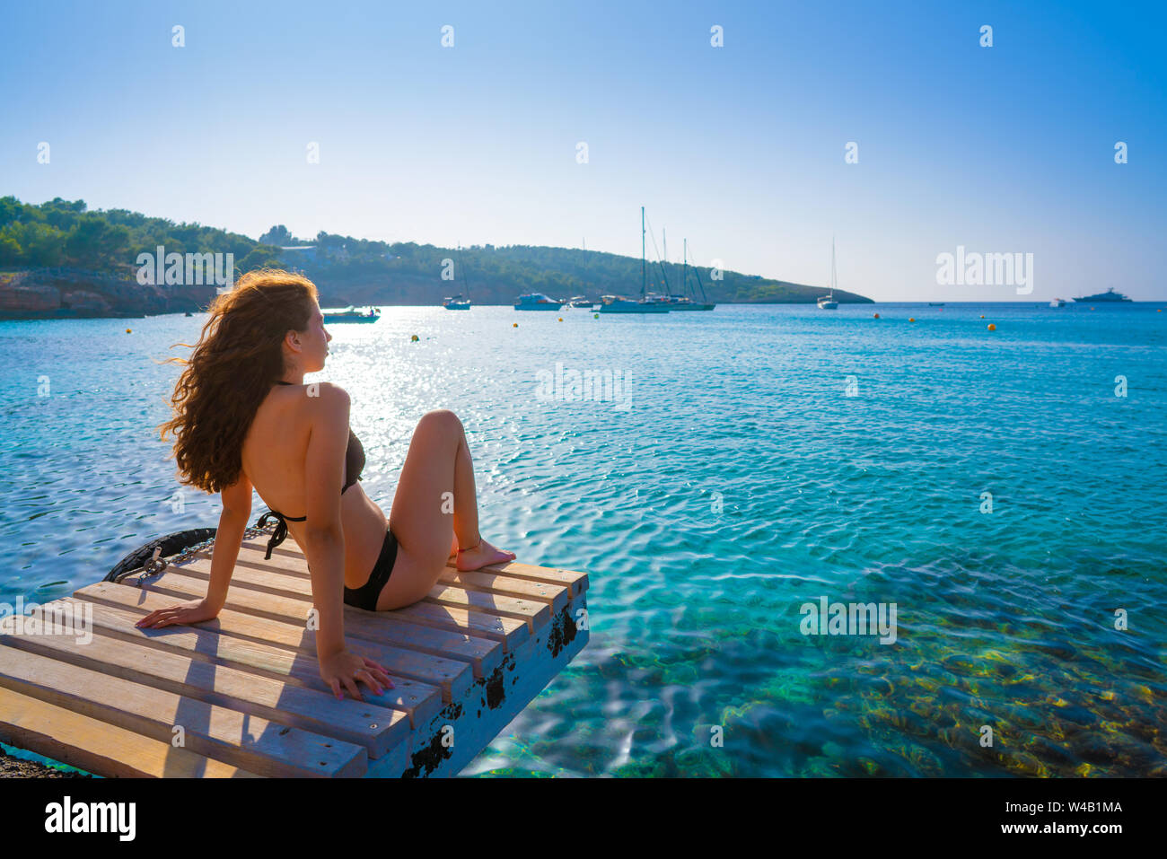 Ibiza bikini girl relaxed at Portinatx beach  pier in Balearic Islands Stock Photo