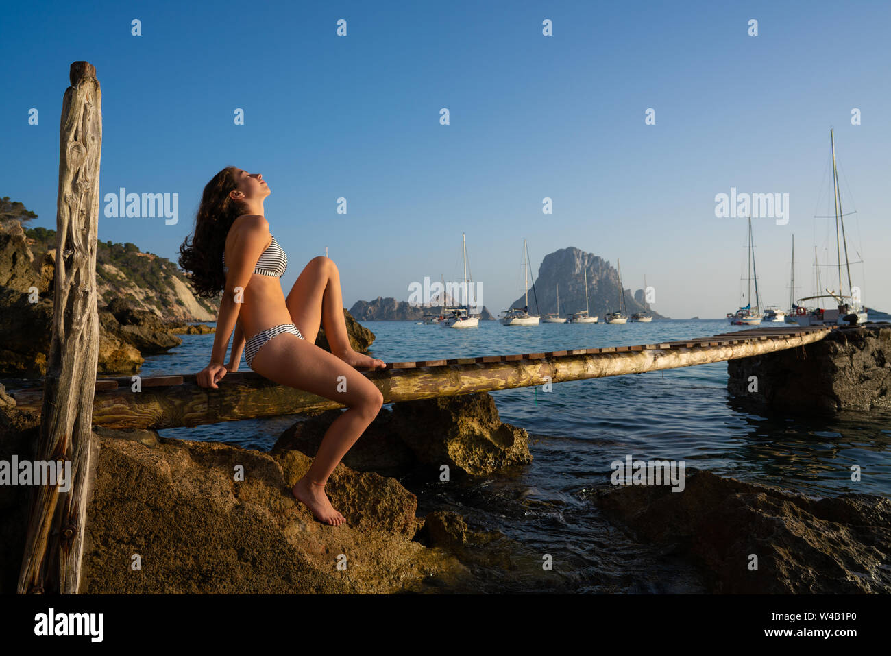 Ibiza cala d Hort girl on pier sunset Es Vedra islet Balearic Islands Stock Photo