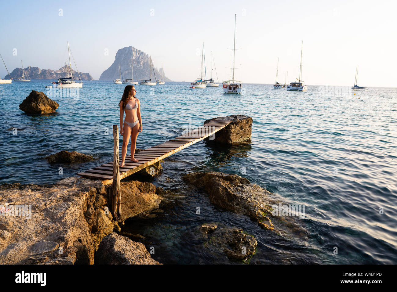 Ibiza cala d Hort girl on pier sunset Es Vedra islet Balearic Islands Stock Photo