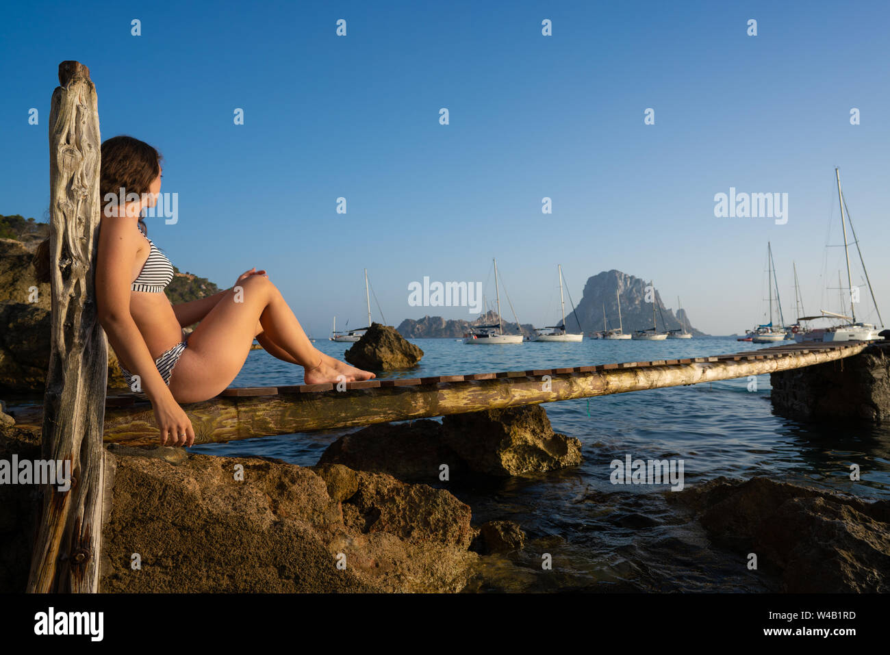 Ibiza cala d Hort girl on pier sunset Es Vedra islet Balearic Islands Stock Photo