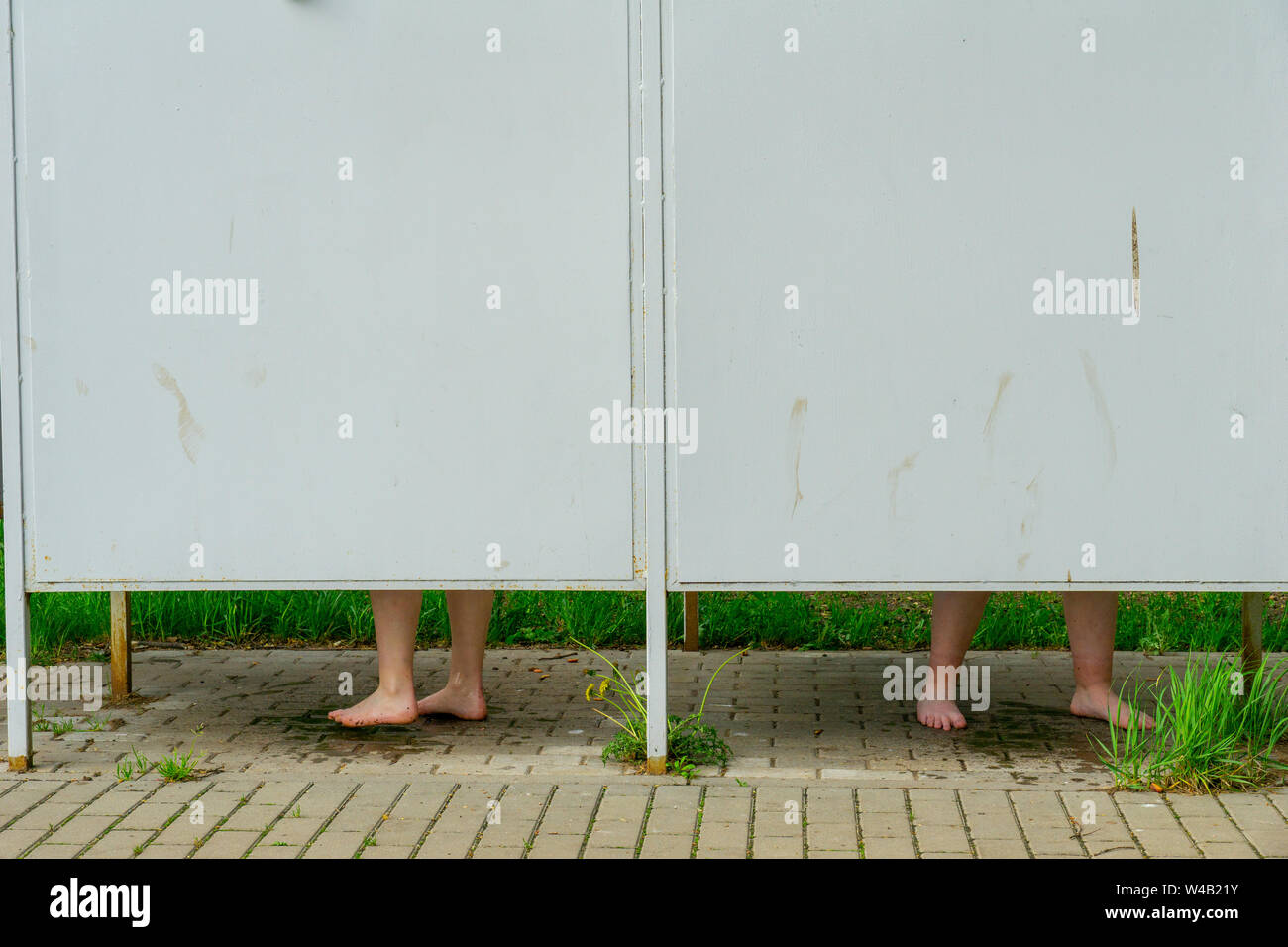Two woman foot standing on the bricked floor without shoes in the changing room by the lake Stock Photo