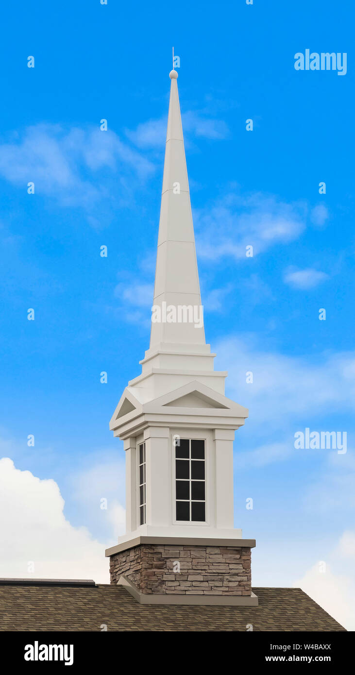 Vertical White steeple on top of the pitched roof of a church with ...