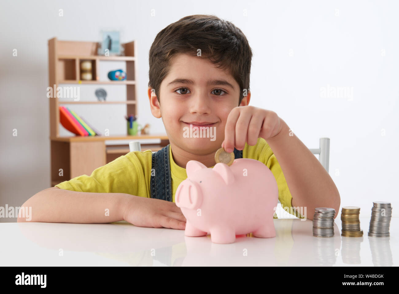 Boy inserting a coin into a piggy bank Stock Photo - Alamy