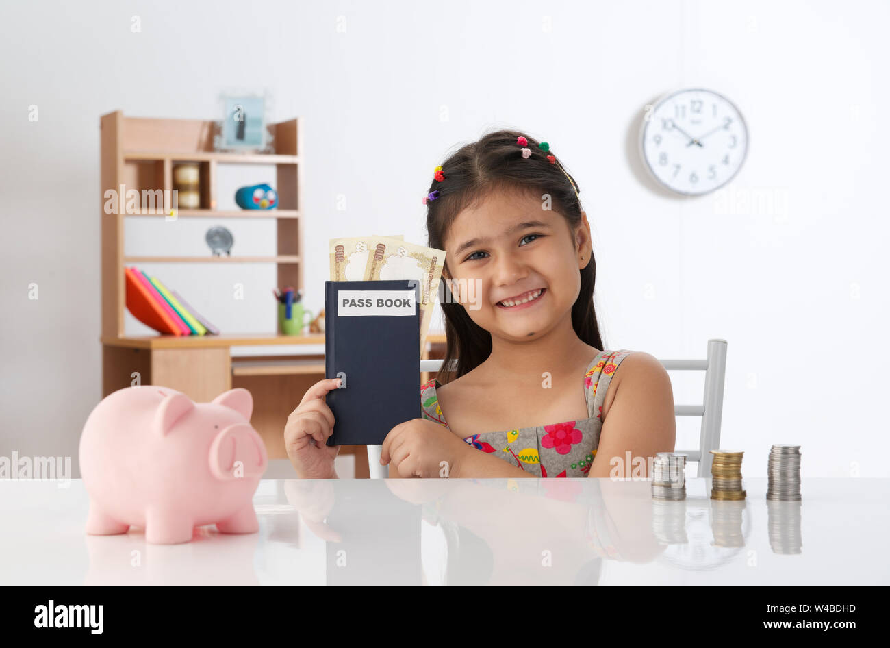 Girl showing bank book with coins and piggy bank Stock Photo - Alamy