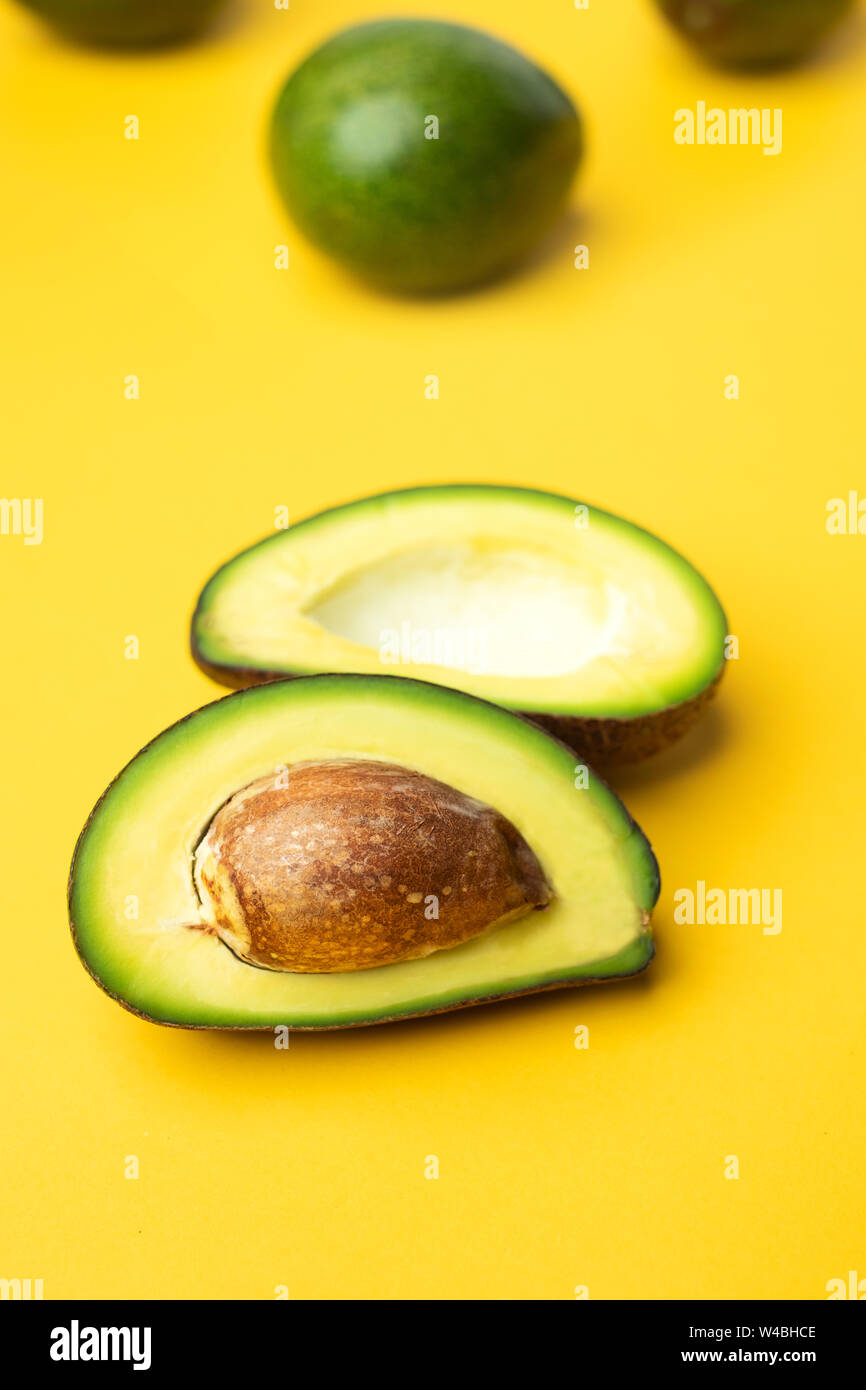 organic avocado and seed half slice and whole fruit on yellow table background.super food keto for diet.close up fresh summer veggie farm concept.nutr Stock Photo