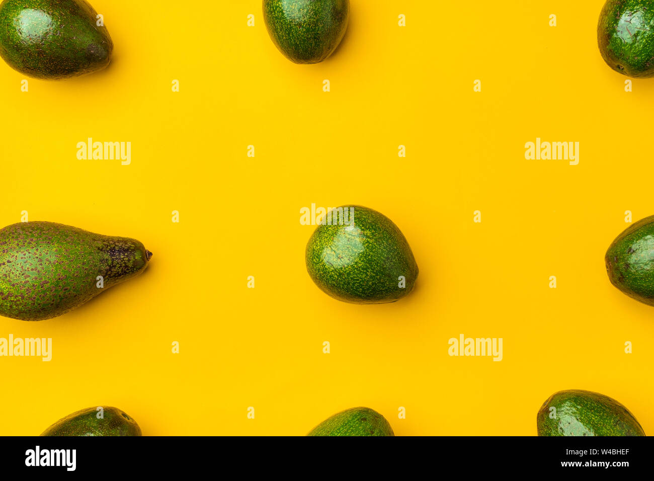 organic avocados whole fruit on yellow table background.Healthy super foods for diet.Fresh vegetable from farm.keto food ingredients.alignment in patt Stock Photo