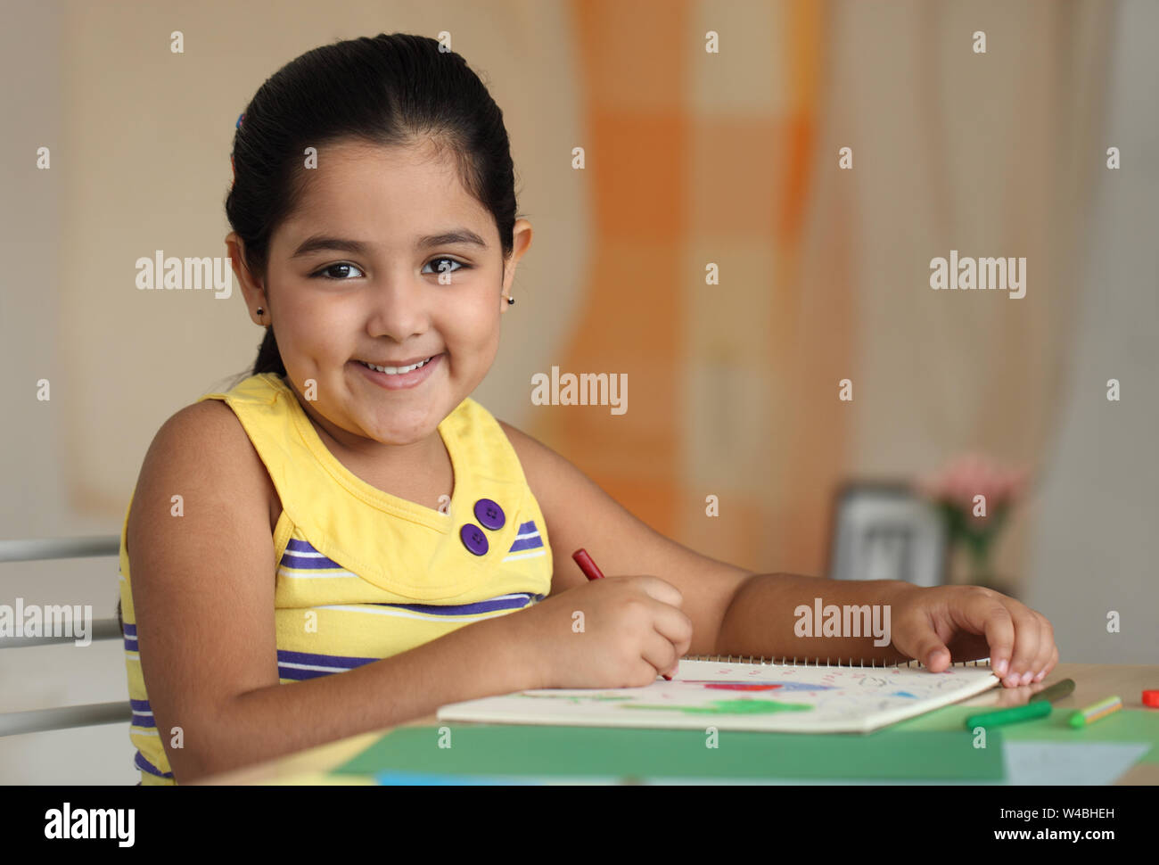 Girl coloring a book and smiling at home Stock Photo - Alamy