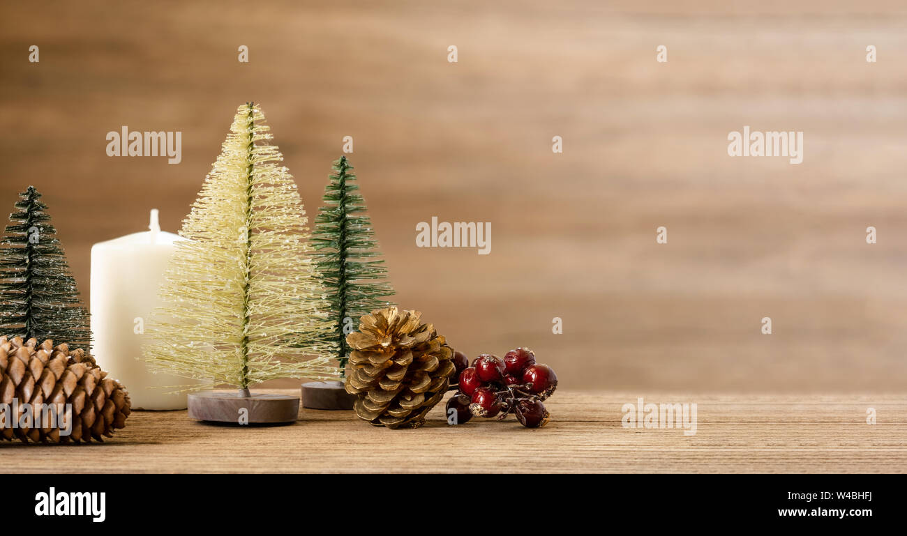 Christmas tree decoration background on wood table with snow.pine cone,mistletoe and bell ball hanging with blur wood wall background.Holiday greeting Stock Photo