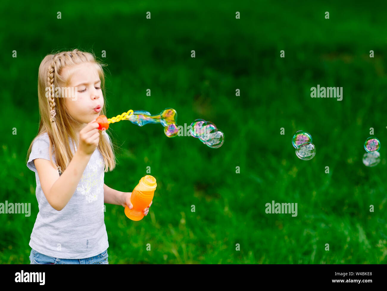 Little girl playing with soap bubbles in the park Stock Photo - Alamy