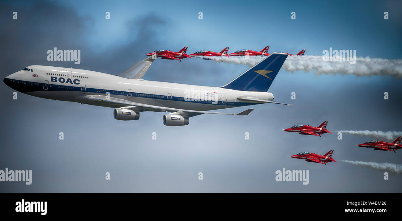Flypast by the RAF Red Arrows aerobatic display team in formation with a BOAC liveried Boeing 747 at The Royal International Air Tattoo, Fairford, UK Stock Photo