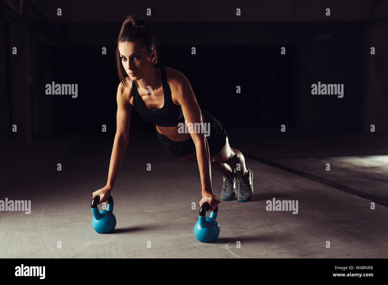 Slim brunette doing push-ups exercises on kettlebells Stock Photo