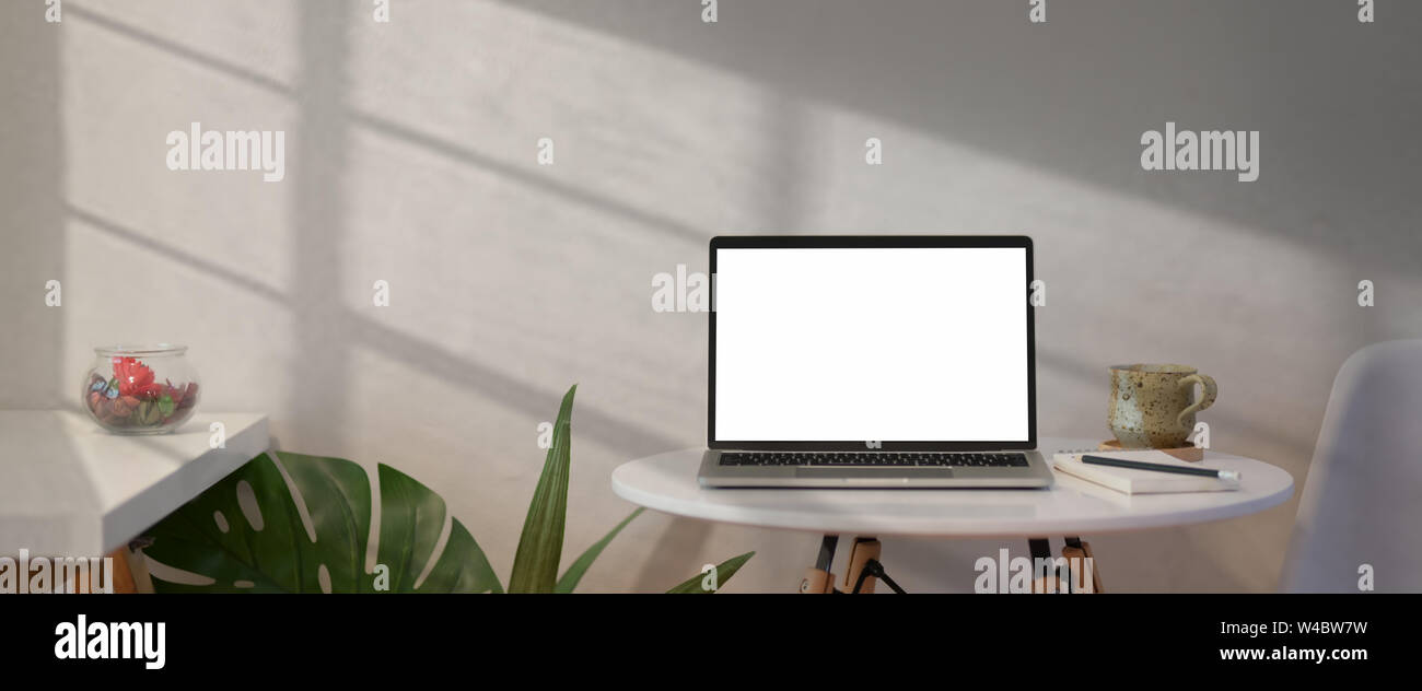 Open laptop with blank screen on white table in loft workspace Stock Photo