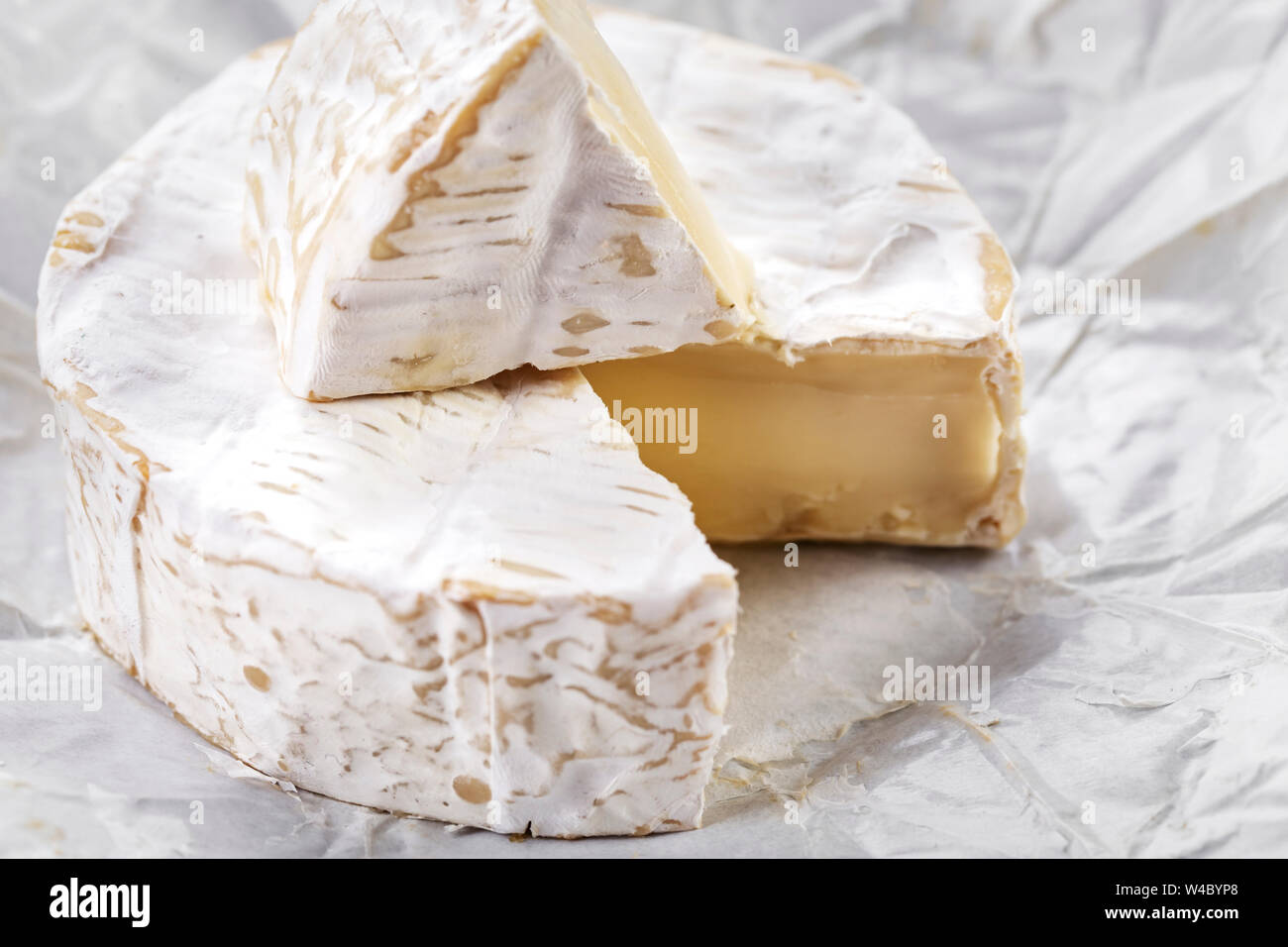 sliced round brie cheese head with white mold on white paper Stock Photo Alamy