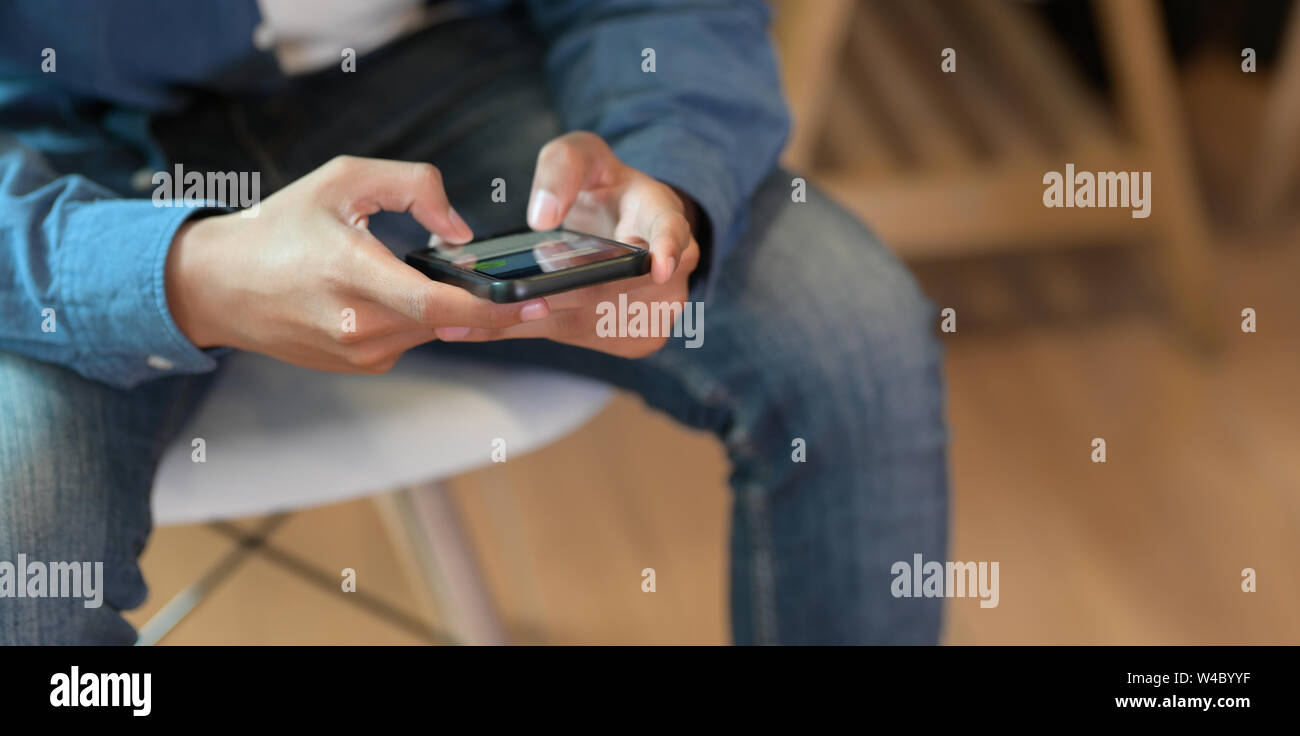 Young male UI developer holding smartphone in relaxing working space Stock Photo