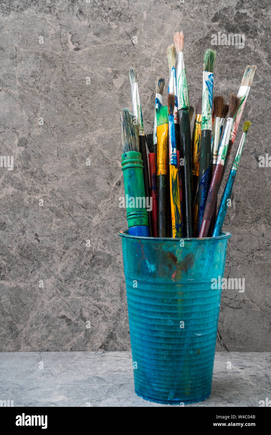 Dirty plastic flask with assorted painting brushes Stock Photo