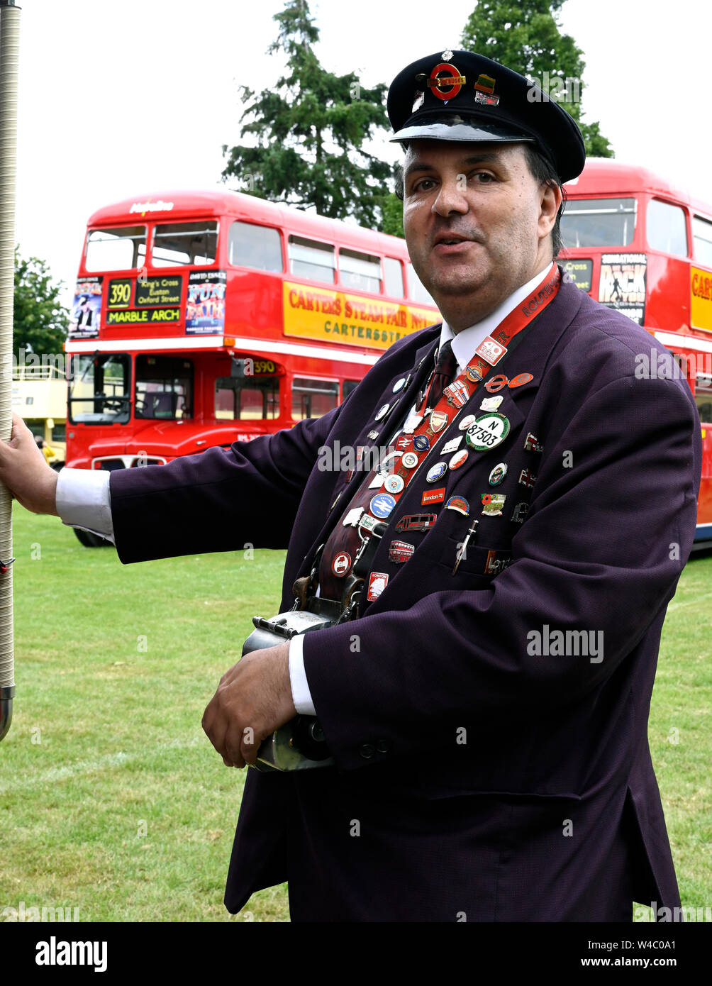 Traditional bus conductor posing with a collection of pin badges. Stock Photo