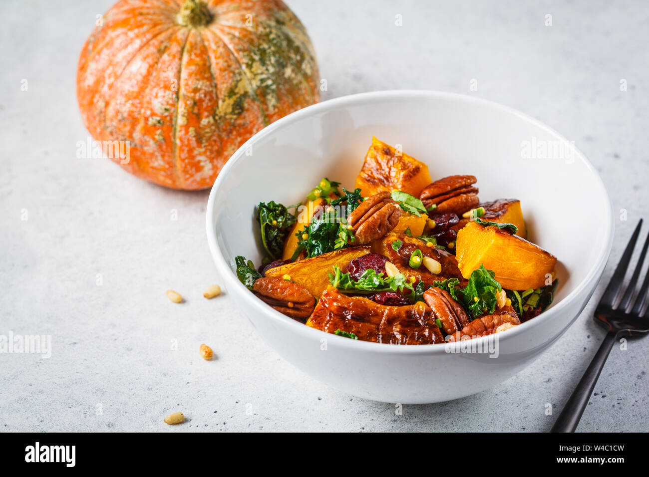 Pumpkin salad with nuts, cranberries and kale in white bowl. Stock Photo