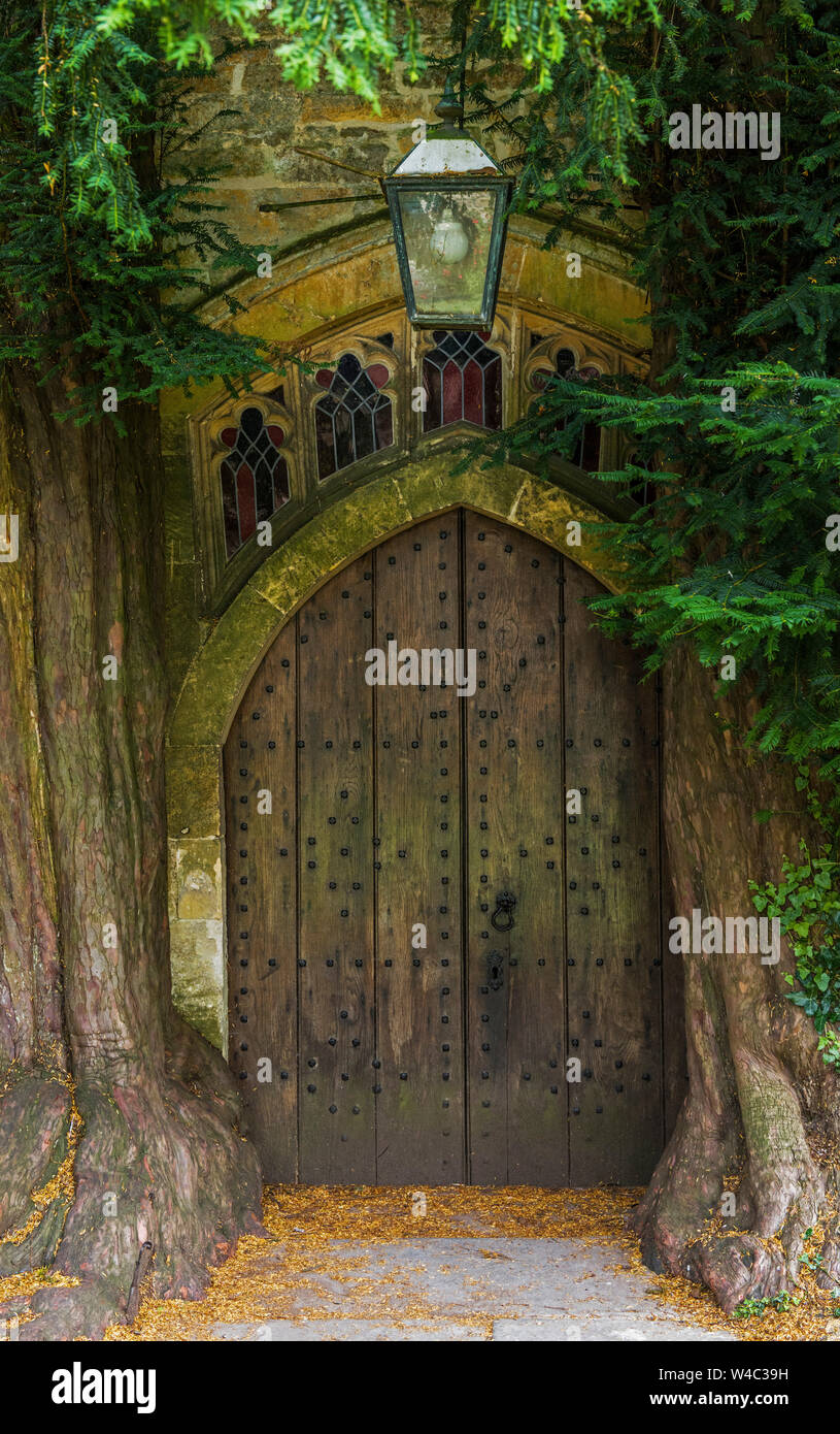 The north wooden door of St Edward's Church in Stow on the Wold in Gloucestershire with ancient yew trees either side Stock Photo