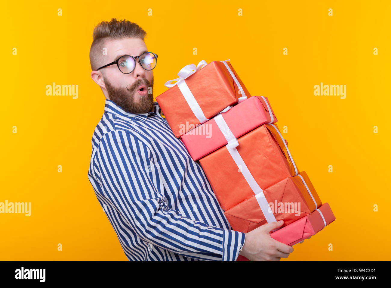 Surprised Young Hipster Guy In Glasses Holding A Large Stack