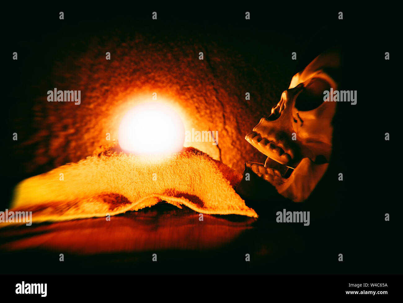 Psychic readings and clairvoyance with human skull and magic ball predictions lighting on dark background , selective focus blur filter Stock Photo