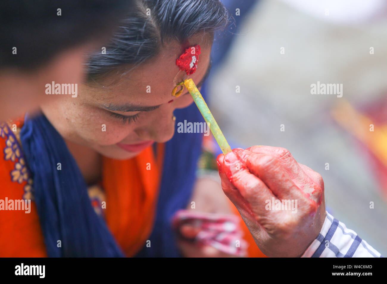 Kathmandu, Nepal. 22nd July, 2019. A devotee takes blessings from a priest after offering her prayers to the Hindu god Lord Shiva, the god of destruction and creation at the Shiva temple during a Shrawan Sombar festival.Shrawan month is considered as the holiest month of the year and each Somvar (Monday) of this month is known as Shrawan Somvar, during which devotees fast and worship Lord Shiva to pray for happiness for their families. Credit: SOPA Images Limited/Alamy Live News Stock Photo