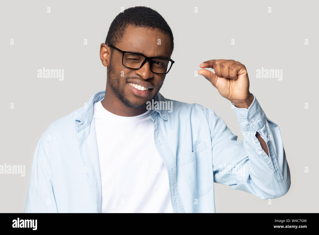 Smiling black male use hand show little measurement gesture Stock Photo