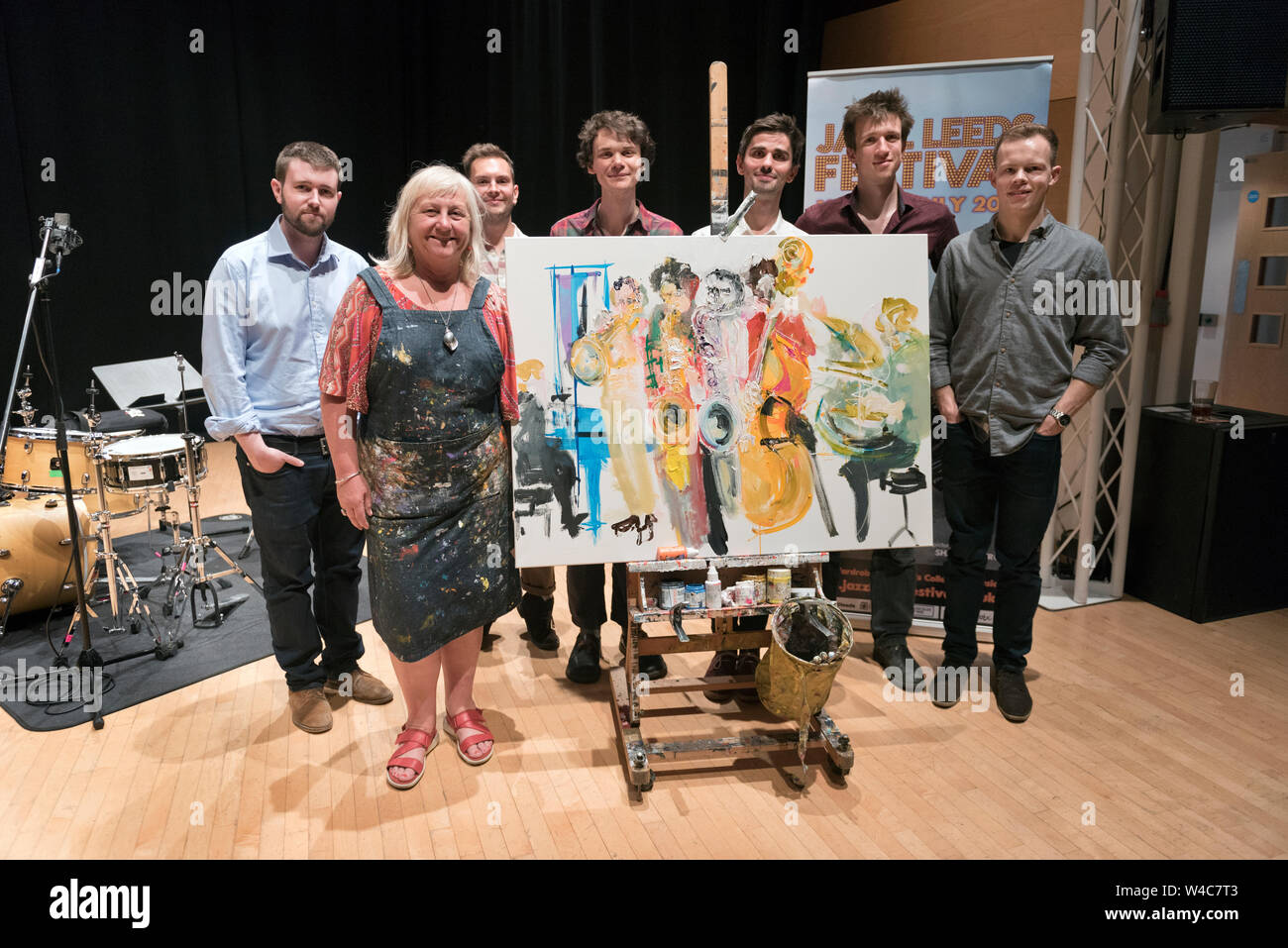 Leeds, UK. 21st July, 2019. Gig painter Gina Southgate poses with the Misha Mullov-Abbado Group, whose performance she has just captured in paint. Gina paints musicians on stage as they perform and painted several acts during the final day (Sunday) of the Leeds Jazz Festival.. Credit: John Bentley/Alamy Live News Stock Photo