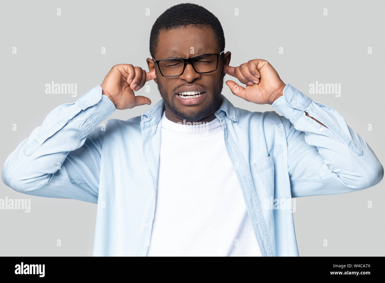 Annoyed black man plug ears avoiding disturbing sound Stock Photo