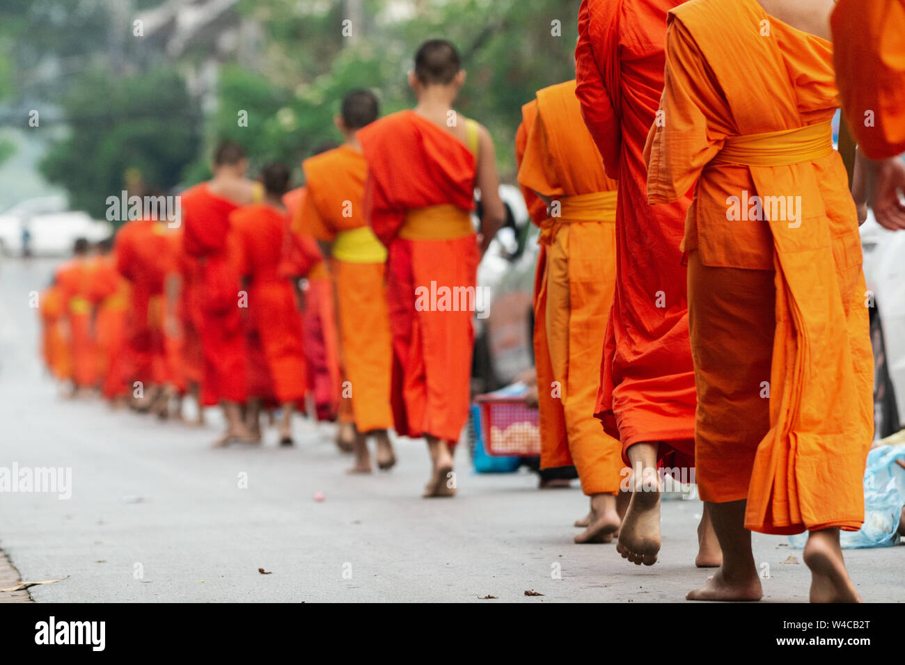 Laotian Buddhist monks walking along the street during morning alms giving ceremony in Luang Prabang, Laos Stock Photo