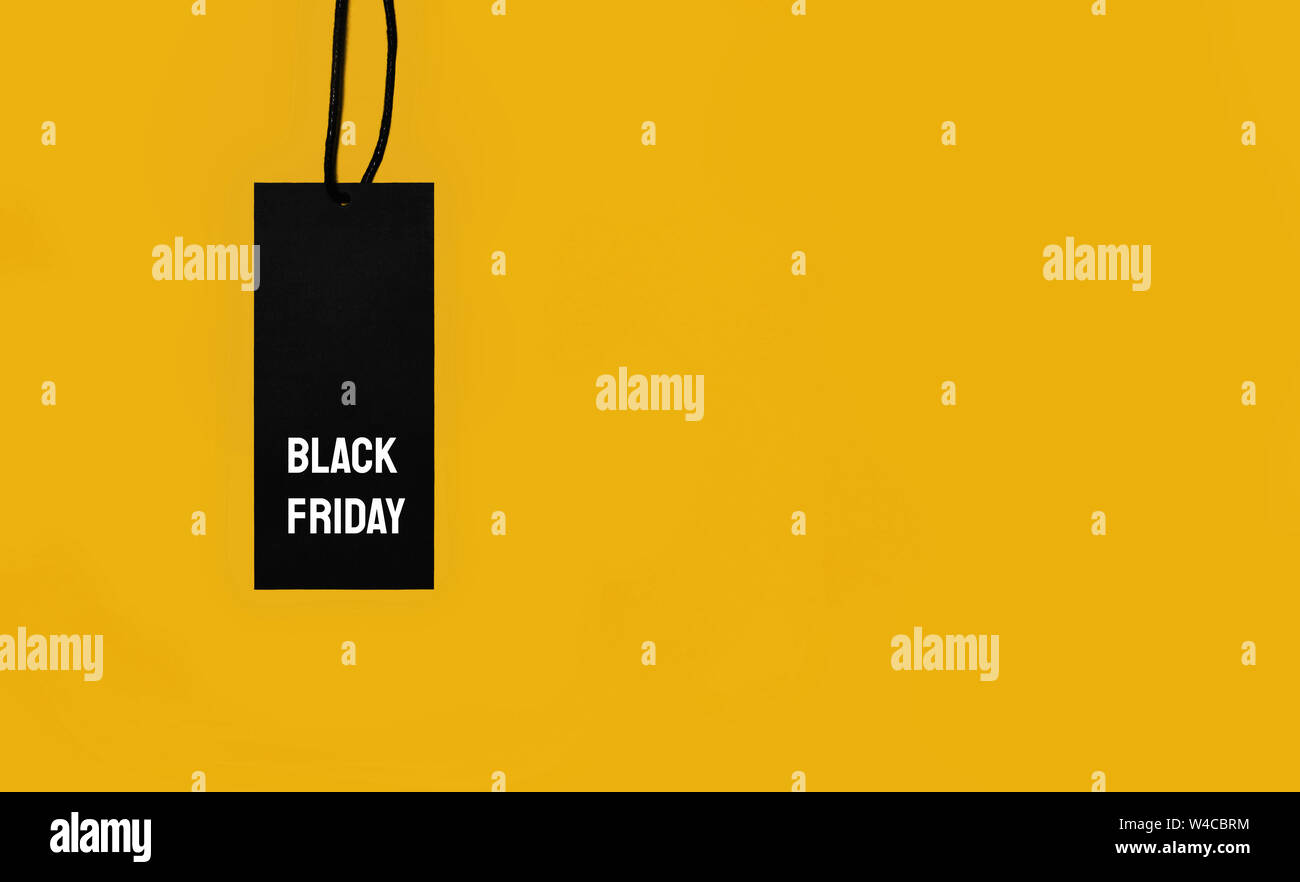 Black sale tag with Black Friday inscription on yellow background. Stock Photo